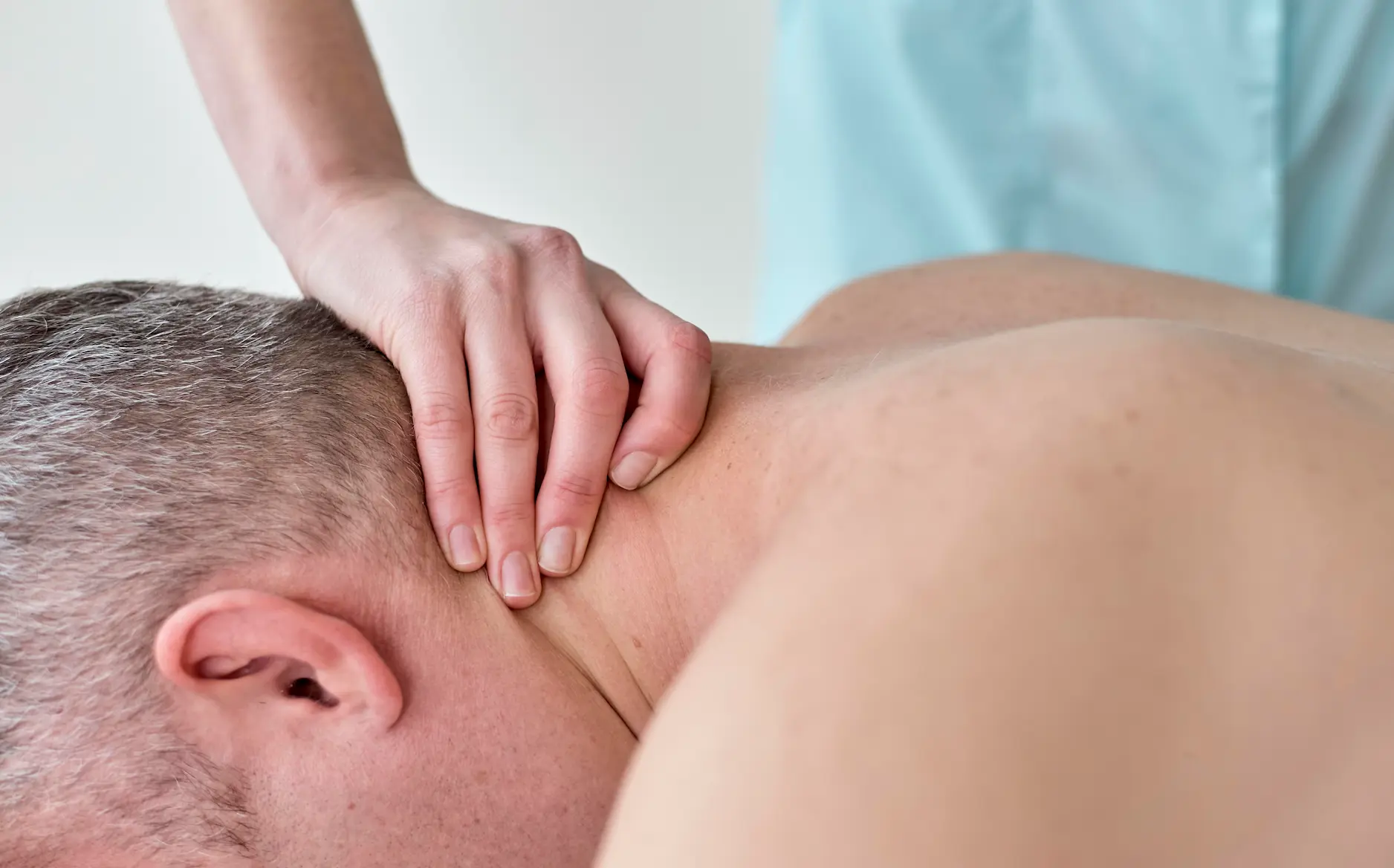 Osteopathische Behandlung eines Mannes an Nacken und Schulter
